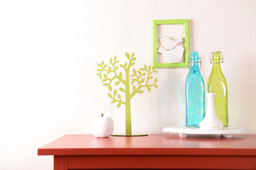 Room interior with red wooden commode and glass bottles on light wall background