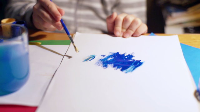 Child painting something on the paper using brush, steadycam shot
