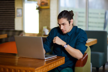 Young man drinking coffee and working on laptop in a cafe