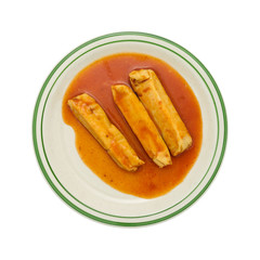 Serving of tamales in chili sauce on plate top view