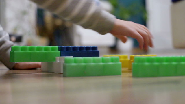 Child sitting on the floor and playing with colorful blocks

