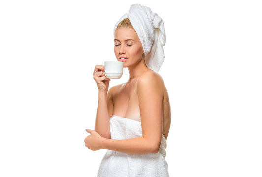 Young woman in towel drinks from a cup 