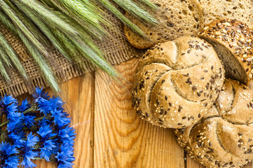 Whole wheat rye bread rolls with ears of cereal and cornflowers