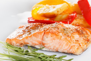 Grilled salmon fillet with vegetables, spices and arugula on a plate