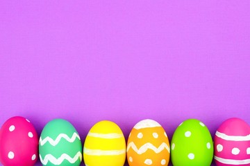 Colorful Easter egg bottom border over a soft purple paper background