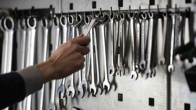man takes a wrench and hangs back