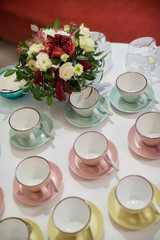 Colorful cups in front of flowers