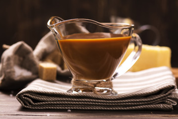 Caramel sauce and ingredients over grunge wooden background. Rustic style. Toned image. Selective focus