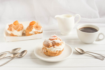 Homemade fresh cream puff with whipped cream and apricots , cup of coffee and milk jug. Toning.