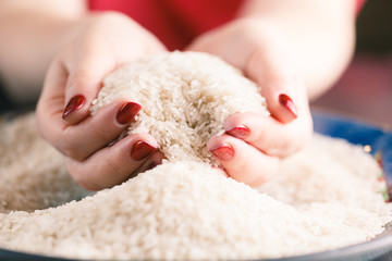 Two hands with rice grains over plate