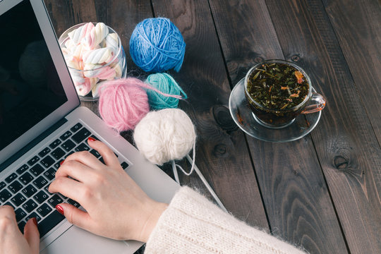 woman is knitting in front of laptop