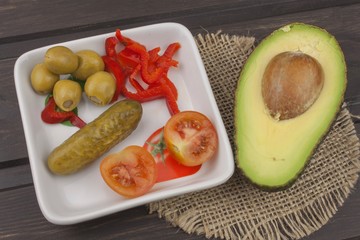 Preparation of dietary avocado salad. Fresh ripe avocado on a wooden background. Food background with fresh organic avocado. Avocado on a dark wood background.
