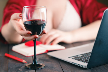 Woman sitting at home table having a glass of red wine