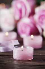 Pink roses and pinl candles on the wooden table