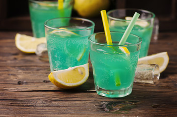 Green cocktail with lemon and ice on the wooden table