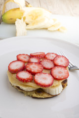 Stack of golden pancakes with strawberries, banana,