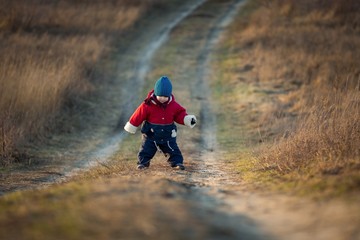 Young happy boy playing outdoor on country road