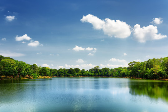 Lake nestled among rainforest in Cambodia under blue sky
