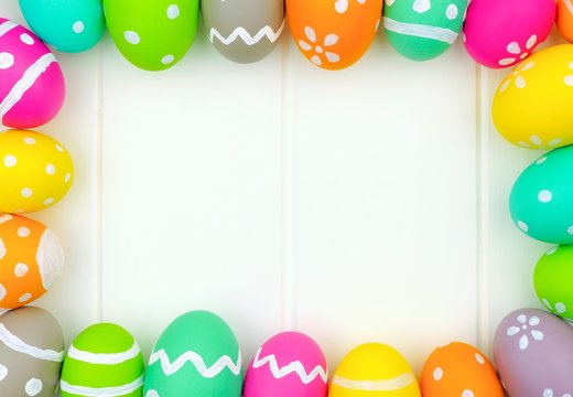 Colorful Easter egg frame around a white wood background