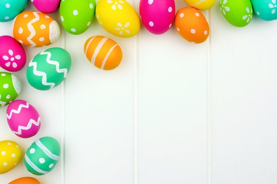 Colorful Easter egg corner border against a white wood background