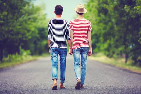 gay couple walking away together on spring road