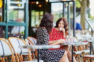 Beautiful twin sisters drinking coffee