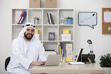 Young happy Arabic business man working on computer in his office