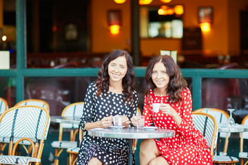 Beautiful twin sisters drinking coffee