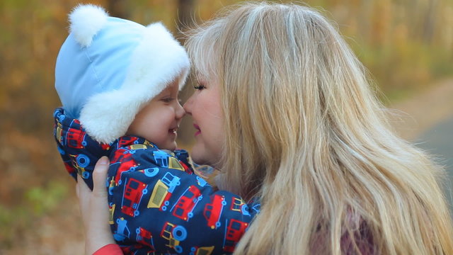 little cute baby kid toddler son in mother's arms on an outdoor stroll.  Child kid with Female, miss, lady. Childhood dreams and memories.