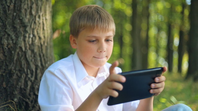 Caucasian child teen boy teenager playing uses touchscreen gadget Tablet PC
