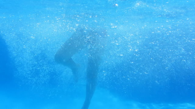 Caucasian child boy teen swims and dives in the pool . Underwater footage