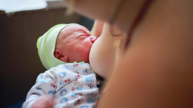 Caucasian newborn baby boy toddler kid near the breast
