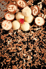 Assorted chocolate candies with flakes on black background