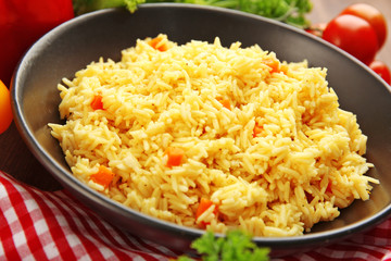 Stewed rice with a carrot on a black plate, close up
