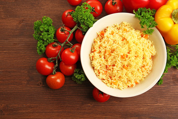 Stewed rice with a carrot on a plate over wooden background