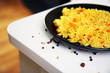 Stewed rice with a carrot on a black plate