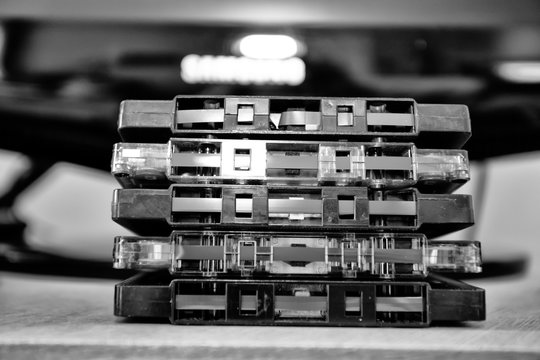 Five cassette tapes stacked on top of each other in black and white