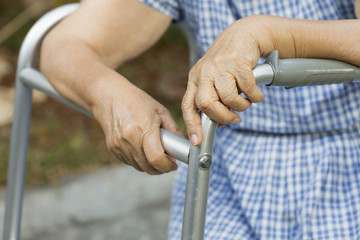 Elderly sitting in backyard with walker.
