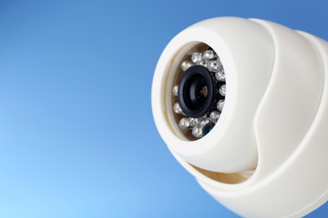Security CCTV camera on blue background, closeup