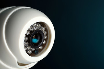 Security CCTV camera on blue background, closeup