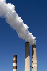 White smoke coming out of power plant chimneys on blue sky background