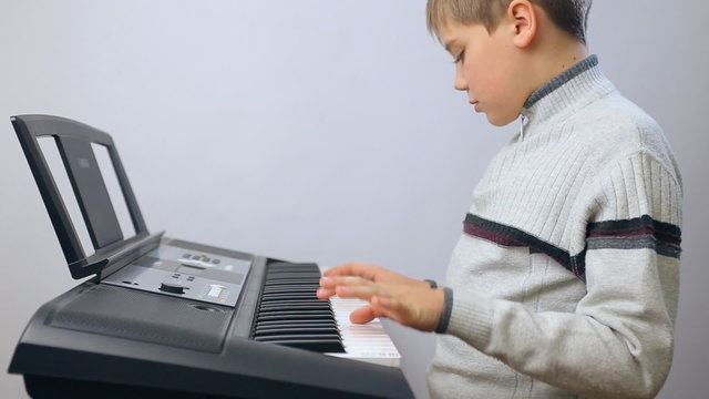Child boy teen keyboardist playing on an electronic keyboard instrument. Gifted kid