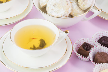 Tea cup with green tea, cookies and chocolate candies.
