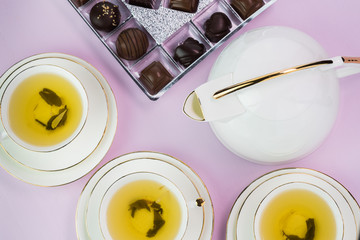Tea cups with green tea and chocolate candies.