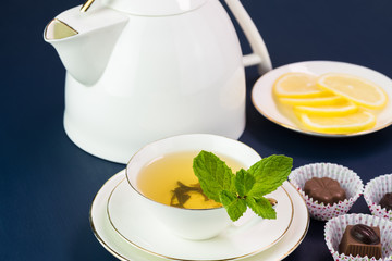 Tea cup with green tea and teapot.