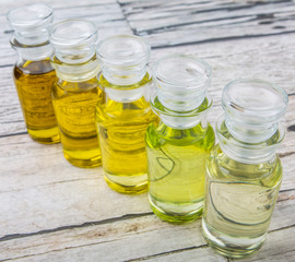 Avocado fruit oil, sesame seed oil, olive oil, grape seed oil and corn oil in vial glass bottle over rustic wooden background