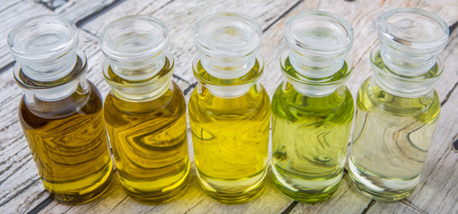 Avocado fruit oil, sesame seed oil, olive oil, grape seed oil and corn oil in vial glass bottle over rustic wooden background