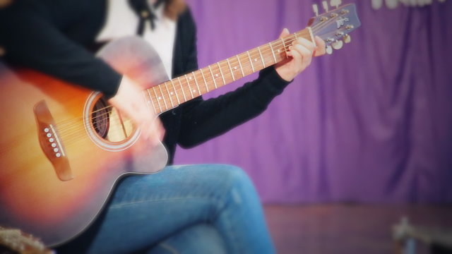 Teen Girl guitarist with an acoustic guitar at a school concert. Female, miss, lady