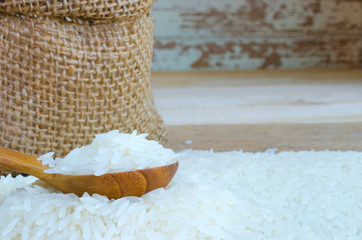 Rice in small hemp sacks and in wooden spool on wooden backgroun