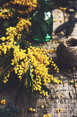 Decoration with bunch of mimosa, scissors and green bottle on ru